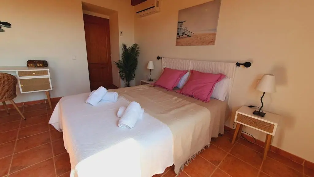 Schlafzimmer mit weißer Bettwäsche und Holzmöbeln